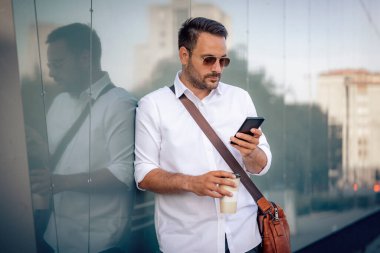 Şehirde akıllı telefon kullanan yakışıklı bir iş adamı. Açık havada genç bir iş adamının portresi..