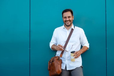 Yakışıklı iş adamı dışarıda poz veriyor ve kameraya bakıyor..