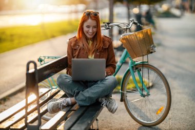 Dışarıda dizüstü bilgisayarda çalışan güzel bir bayan serbest yazar. Uzaktan kumanda..