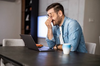 Stresli adam faturalardaki kötü haberi gördü. Evde dizüstü bilgisayara bakan hayal kırıklığına uğramış işsiz bir adam. Finansal sorunlar, durgunluk ve iflas kavramı..