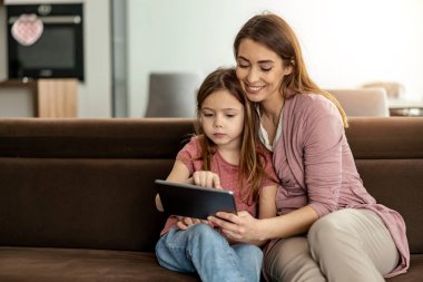 Mutlu anne ve kızı online dersler için dijital tablet kullanıyorlar. Online okul konsepti..