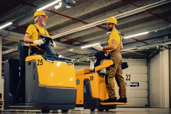 İş yerinde elektrikli forklift kullanan işçiler. Ticarette siparişleri taşıma ve işleme.