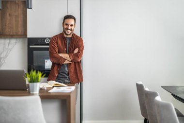 Yeni proje üzerinde çalışan erkek tasarımcı. Ev ofisinde çalışan genç yaratıcı adam. Kameraya bakıyor..