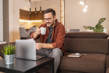 Dizüstü bilgisayar kullanan, e-posta yazan, online görüşme ya da internet üzerinden ödeme yapan bir adam. Ev ofisinden çalışan serbest çalışan biri..