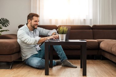 Genç adam ev işlerinde çalışıyor. Erkek mimar dizüstü bilgisayarda çalışıyor..