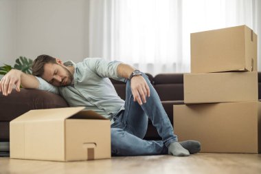 Hayal kırıklığına uğramış bir adam oturma odasında karton kutuların yanında uyuyor, mali sorunları var, boşandıktan sonra yalnız kalıyor..