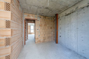 İnşaat halindeki binanın içinde bitmemiş bir oda. Tuğla kırmızı duvarlar. Yeni ev.