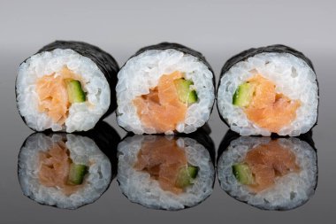 Set of three sushi rolls with salmon and avocado. Sushi with reflection. Traditional japanese food