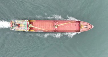 Açık denizde yelken açan kırmızı bir kargo gemisinin yukarıdan görünen görüntüsü. Gemi lojistik ve ulaşım endüstrisi.