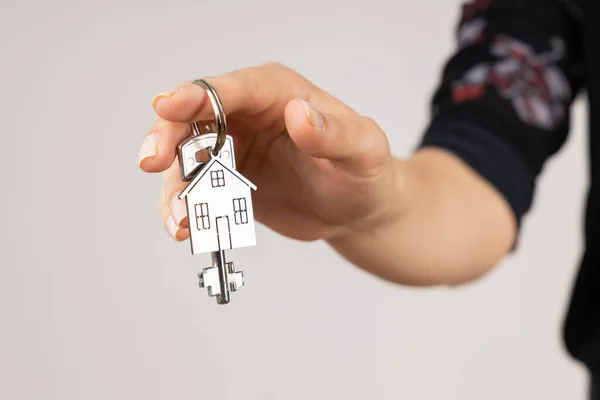 女性の手は 家庭の形のキーチェーンと新しい金属キーを与え 隔離された 新しいホームコンセプト — ストック写真