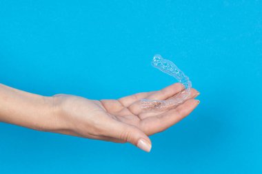 Woman hand holding Invisible tooth brackets. Dental healthcare and Orthodontic concept. Inivisalign braces or aligner