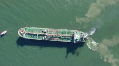 Top down view of Tug boat assisting big oil, chemical tanker. Large oil, chemical tanker ship enters the port escorted by tugboat.