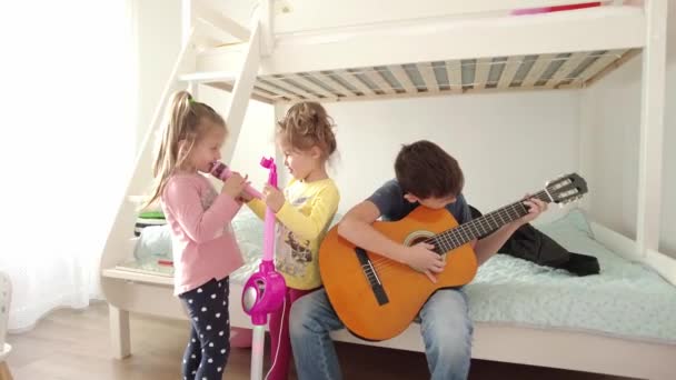 快乐的兄弟姐妹们一边弹吉他一边唱歌 哥哥弹吉他 姐姐们唱 — 图库视频影像