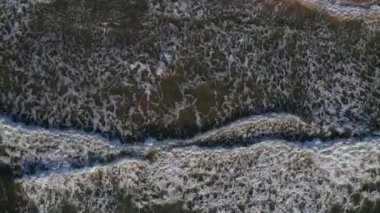 Top down view of breaking waves, whitewash. Huge swell hitting shoreline.