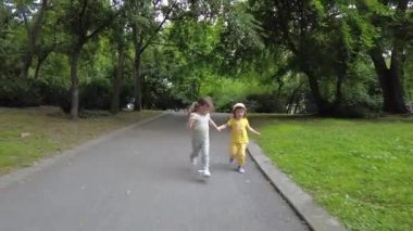 Parkta koşan iki küçük kız. Mutlu kız kardeşler, eğleniyorlar. Aile aktivitesi açık havada.