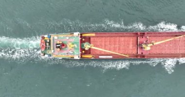 Açık denizde yelken açan kırmızı bir kargo gemisinin yukarıdan görünen görüntüsü. Gemi lojistik ve ulaşım endüstrisi.