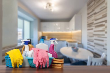 Home cleaning service concept with supplies. Close up of cleaning supplies in front of livingroom. clipart