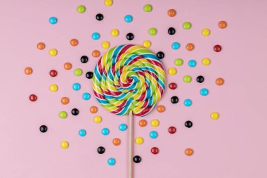 Tatlı lolipop ve pembe arka planda renkli şeker hapları. 