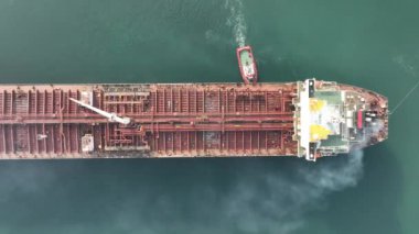 Büyük petrol tankerine yardım eden römorkör görüntüsü. Römorkör eşliğinde büyük bir petrol tankeri limana giriyor..