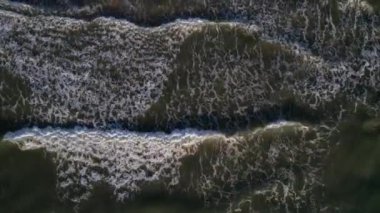 Top down view of breaking waves, whitewash. Huge swell hitting shoreline.