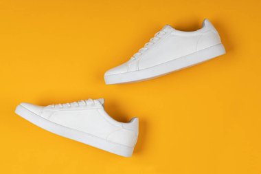 Çift sarı arka plan üzerinde yeni beyaz spor ayakkabı