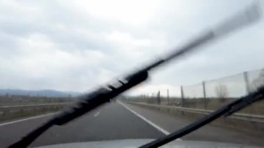Yağmurda Araba Kullanmak. Arabanın ön camında yağmur damlaları olan içeriden görünüm.