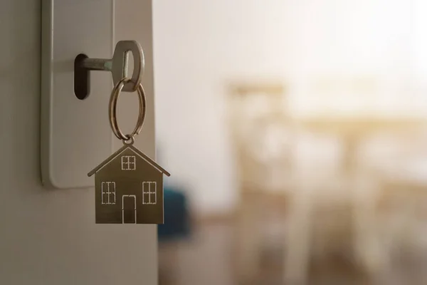 キーとホーム形状のキーチェーンを持つ新しい家への扉を開きます 住宅ローン 不動産 不動産と新しい家の概念 — ストック写真