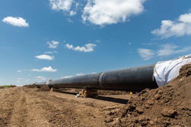 Gaz ve petrol boru hattı inşaatı. Borular kaynaşmış. Büyük boru hattı yapım aşamasında. Bulutlu gökyüzü