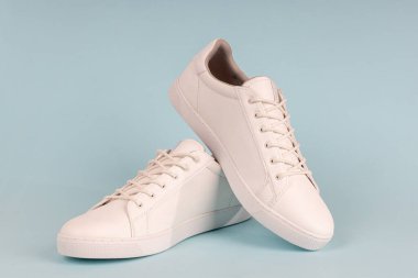 Mavi arka planda bir çift yeni beyaz spor ayakkabı