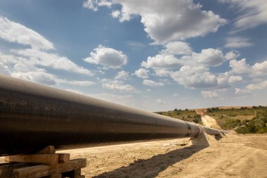 Gaz ve petrol boru hattı inşaatı. Borular kaynaşmış. Büyük boru hattı yapım aşamasında. Bulutlu gökyüzü