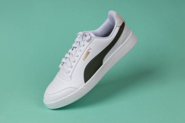 Varna, Bulgaristan - 13 Ekim 2023. Yeşil arka planda beyaz PUMA Shuffle spor ayakkabıları. Puma, büyük bir Alman çokuluslu şirketi. Ürün çekimi