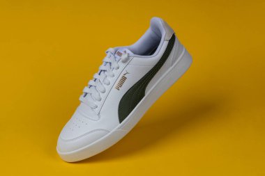 Varna, Bulgaristan - 13 Ekim 2023. Sarı arka planda beyaz PUMA Shuffle spor ayakkabıları. Puma, büyük bir Alman çokuluslu şirketi. Ürün çekimi