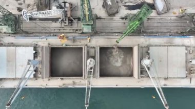 Limandaki vinçlerle ayçiçeği taşıyan kuru kargo gemisi yükleniyor. Deniz kargo gemisinin ambarına hava görüntüsü yükleniyor