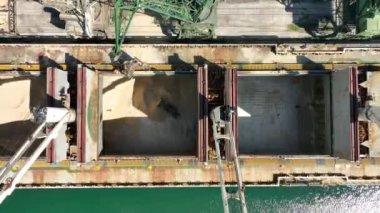 Limanda vinçlerle kuru kargo gemisi boşaltılıyor. Kargo ambarında çalışan buldozerin hava görüntüsü