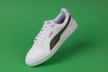 Varna, Bulgaristan - 13 Ekim 2023. Yeşil arka planda beyaz PUMA Shuffle spor ayakkabıları. Puma, büyük bir Alman çokuluslu şirketi. Ürün çekimi