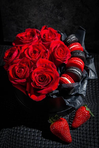 Present box with red roses and macaroons, decorated with strawberries. Background for valentines and woman day. Wedding decoration