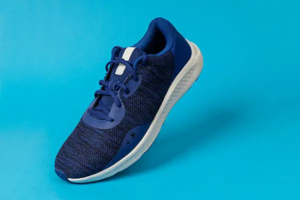 Running sports shoe on blue background. Running shoe, sneaker or trainer. Men\'s athletic shoe. fitness, sport, training concept.