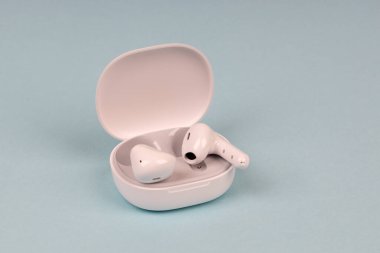 Mavi arka planda beyaz kablosuz kulaklık. Yeni kulaklıklar. Yeni teknolojiler.