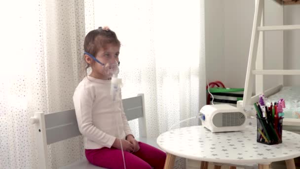吸入器のマスクのかわいい女の子 自宅で吸入の手順 ネブライザーで呼吸療法を受けている子供 — ストック動画