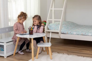 Şirin çocuklar evde bir kitap okuyorlar. İki kız kardeş kitap okuyor ve eğleniyorlar..