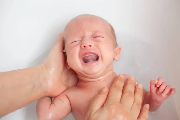 新生儿正在被他的母亲洗澡时 洗澡时新生儿哭了 图库图片