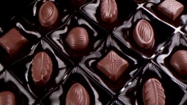 Bir kutu çikolatalı bonbon dönüyor. Karışık çikolataları yakın..