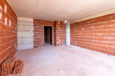İnşaat halindeki binanın içinde bitmemiş bir oda. Tuğla kırmızı duvarlar. Yeni ev.