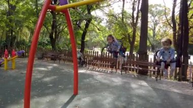 İki küçük kız, oyun alanında oynuyorlar. Çift yumurta ikizi kardeşler, salıncakta sallanıyorlar