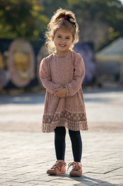 Tatlı küçük kız poz veriyor ve gülümsüyor.