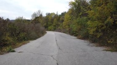 Kırsaldaki boş eski asfalt yolda yürüyorum.