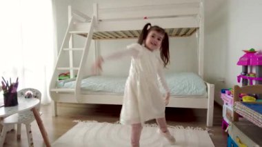 Tatlı küçük kız dans ediyor ve evde eğleniyor.