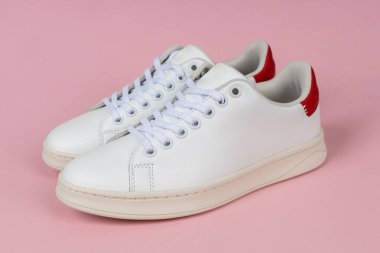 Pembe arka planda bir çift sıradan ayakkabı. Kadın spor ayakkabıları..