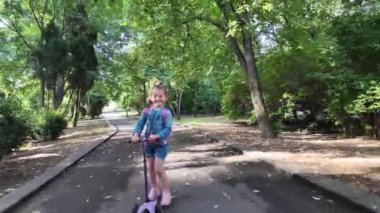 Parkta scooter süren mutlu küçük kız. Şirin kız scooter sürmekten hoşlanıyor.