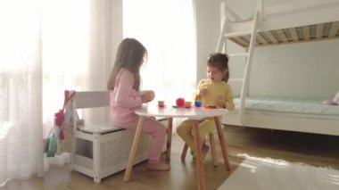 Evde plastik oyuncak mutfağıyla oynayan sevimli küçük kızlar..